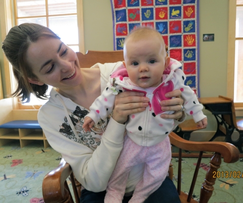 Smiling mom with baby sitting in rocking chair.