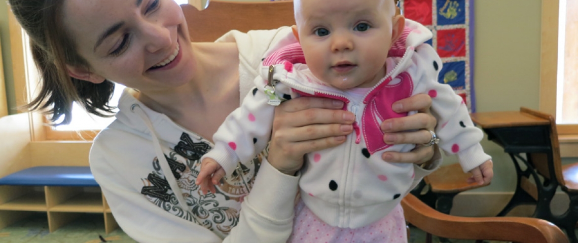 Smiling mom with baby sitting in rocking chair.